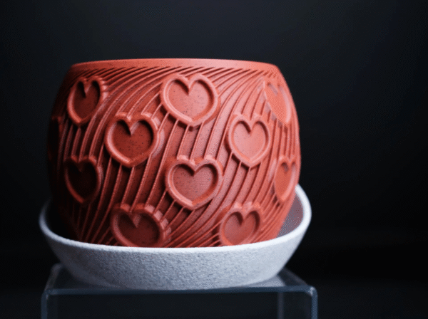 HEART – esencja uczuć w formie designu Doniczka HEART to manifest emocji zamknięty w geometrycznej perfekcji. Stworzona z myślą o wyjątkowych chwilach, stanowi niebanalny prezent dla ukochanej osoby – pełen symboliki, a zarazem absolutnie współczesny. Na powierzchni eleganckiego korpusu w odcieniu klasycznej czerwieni wyrzeźbiono rytmiczne serca, harmonijnie wtopione w dynamiczne linie przypominające strumień energii lub zakodowane wyznanie. To coś więcej niż doniczka – to designerski artefakt, który celebruje uczucie w jego najczystszej formie. Osadzona w kontrastującej, teksturalnej podstawce, HEART zyskuje charakter obiektu galeryjnego, a nie tylko użytkowego. Doskonała na Walentynki, rocznicę, dzień zaręczyn lub jako intymny gest bez okazji. Dostępna w wymiarach: 130 × 130 × 100 mm (szerokość × głębokość × wysokość) Podaruj coś, co nie zwiędnie. HEART – design, który mówi „kocham” bez słów.