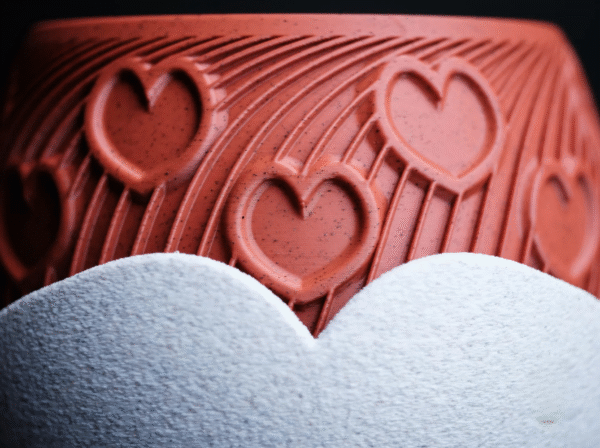 HEART – esencja uczuć w formie designu Doniczka HEART to manifest emocji zamknięty w geometrycznej perfekcji. Stworzona z myślą o wyjątkowych chwilach, stanowi niebanalny prezent dla ukochanej osoby – pełen symboliki, a zarazem absolutnie współczesny. Na powierzchni eleganckiego korpusu w odcieniu klasycznej czerwieni wyrzeźbiono rytmiczne serca, harmonijnie wtopione w dynamiczne linie przypominające strumień energii lub zakodowane wyznanie. To coś więcej niż doniczka – to designerski artefakt, który celebruje uczucie w jego najczystszej formie. Osadzona w kontrastującej, teksturalnej podstawce, HEART zyskuje charakter obiektu galeryjnego, a nie tylko użytkowego. Doskonała na Walentynki, rocznicę, dzień zaręczyn lub jako intymny gest bez okazji. Dostępna w wymiarach: 130 × 130 × 100 mm (szerokość × głębokość × wysokość) Podaruj coś, co nie zwiędnie. HEART – design, który mówi „kocham” bez słów.
