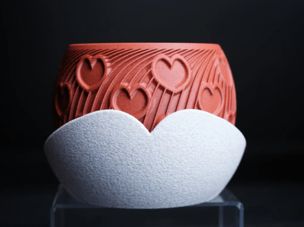 HEART – esencja uczuć w formie designu Doniczka HEART to manifest emocji zamknięty w geometrycznej perfekcji. Stworzona z myślą o wyjątkowych chwilach, stanowi niebanalny prezent dla ukochanej osoby – pełen symboliki, a zarazem absolutnie współczesny. Na powierzchni eleganckiego korpusu w odcieniu klasycznej czerwieni wyrzeźbiono rytmiczne serca, harmonijnie wtopione w dynamiczne linie przypominające strumień energii lub zakodowane wyznanie. To coś więcej niż doniczka – to designerski artefakt, który celebruje uczucie w jego najczystszej formie. Osadzona w kontrastującej, teksturalnej podstawce, HEART zyskuje charakter obiektu galeryjnego, a nie tylko użytkowego. Doskonała na Walentynki, rocznicę, dzień zaręczyn lub jako intymny gest bez okazji. Dostępna w wymiarach: 130 × 130 × 100 mm (szerokość × głębokość × wysokość) Podaruj coś, co nie zwiędnie. HEART – design, który mówi „kocham” bez słów.
